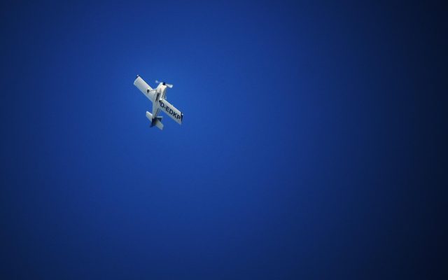 pc12单发涡轮螺旋桨公务机在晴朗蓝天下低空飞行，机翼线条流畅、机身白色涂装配蓝色条纹，展示其优雅的气动外形